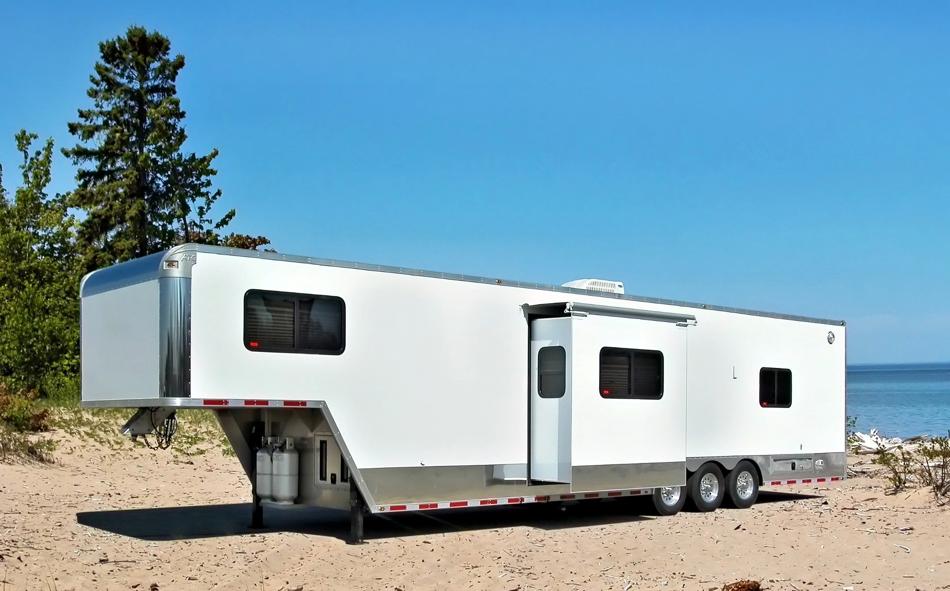 A toy hauler RV parked on a beach.